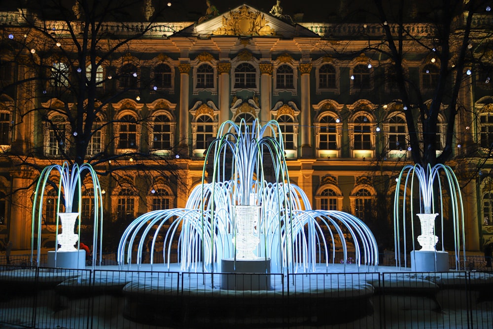 a large fountain in front of a building at night