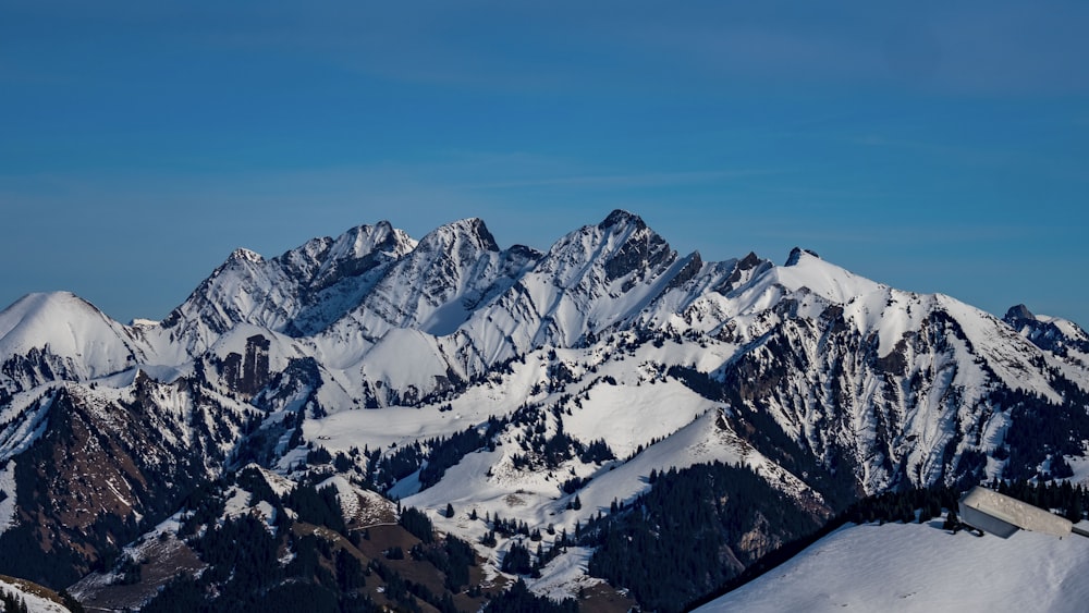 a mountain range covered in snow under a blue sky