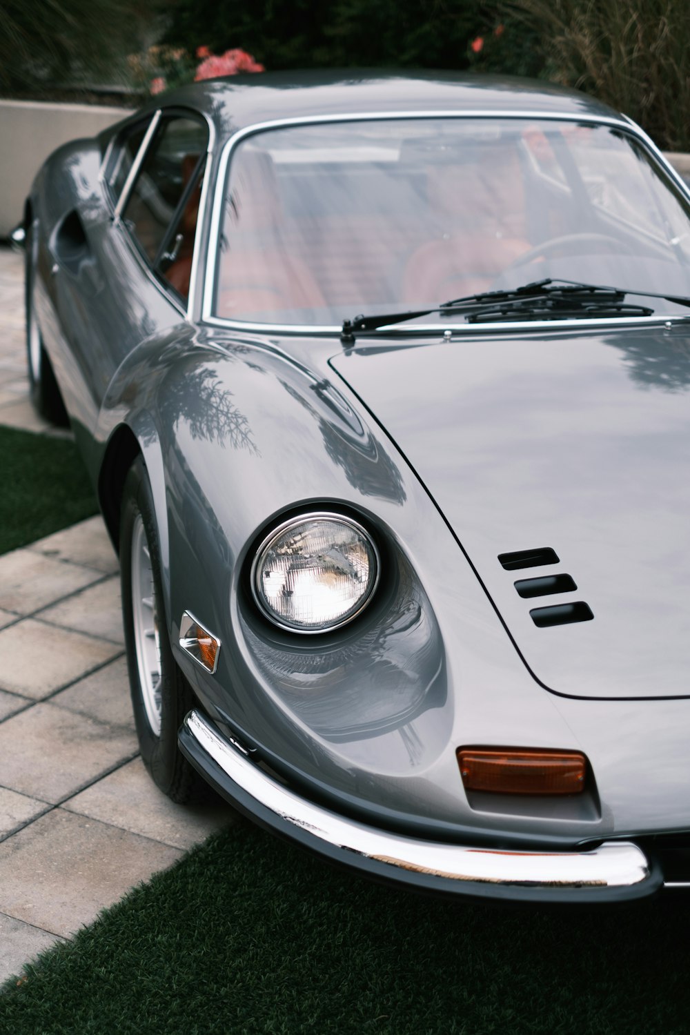 a grey sports car parked on a sidewalk