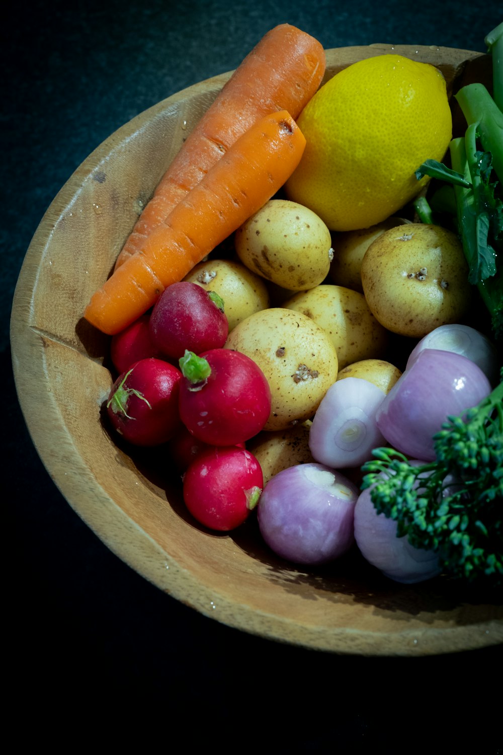 a wooden bowl filled with different types of vegetables