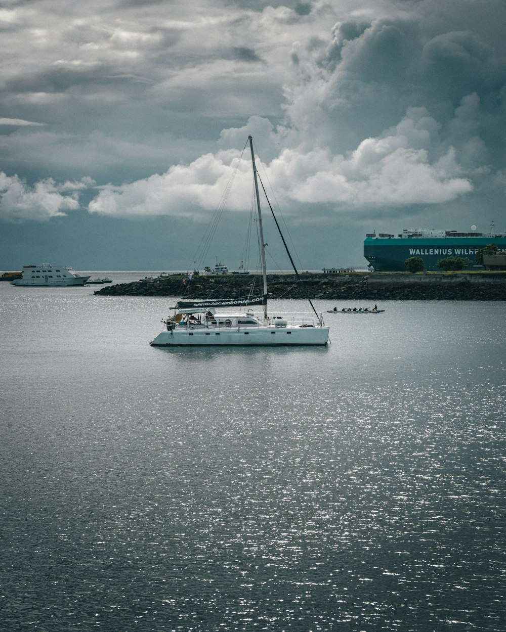 a sailboat floating in the ocean under a cloudy sky