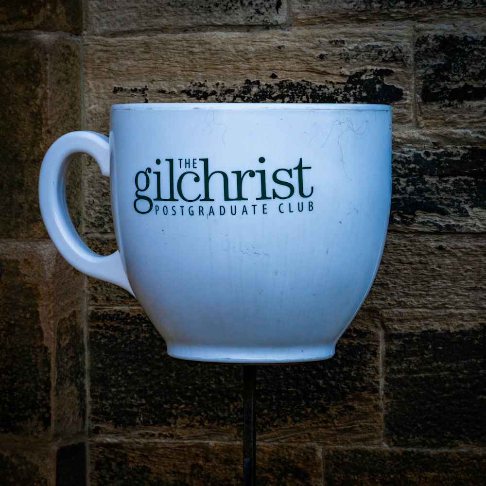 a white coffee cup sitting on top of a metal stand