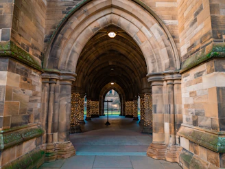 a stone archway with a clock on the wall