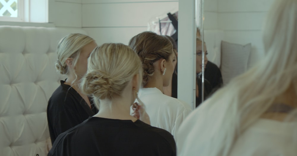 a group of women standing in front of a mirror