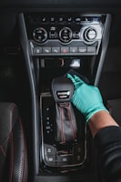 a gloved hand adjusting a car radio in a vehicle