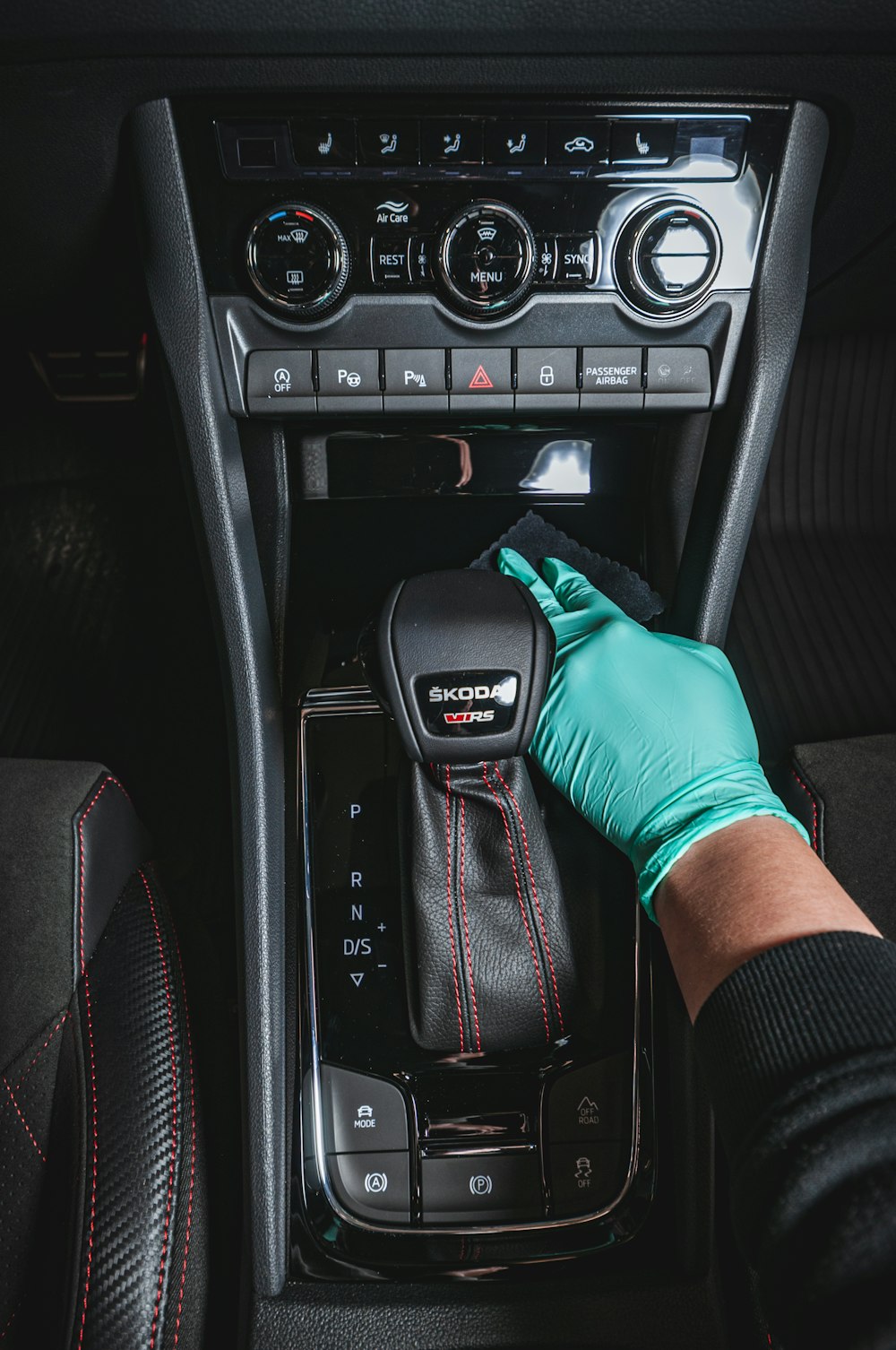 a gloved hand adjusting a car radio in a vehicle