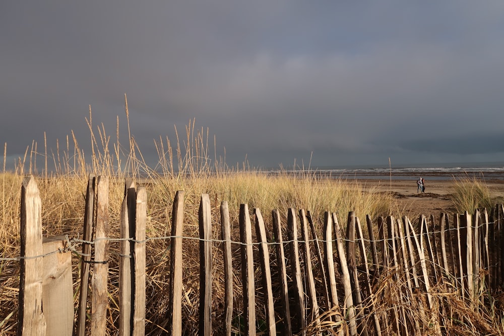 a wooden fence sitting next to a sandy beach