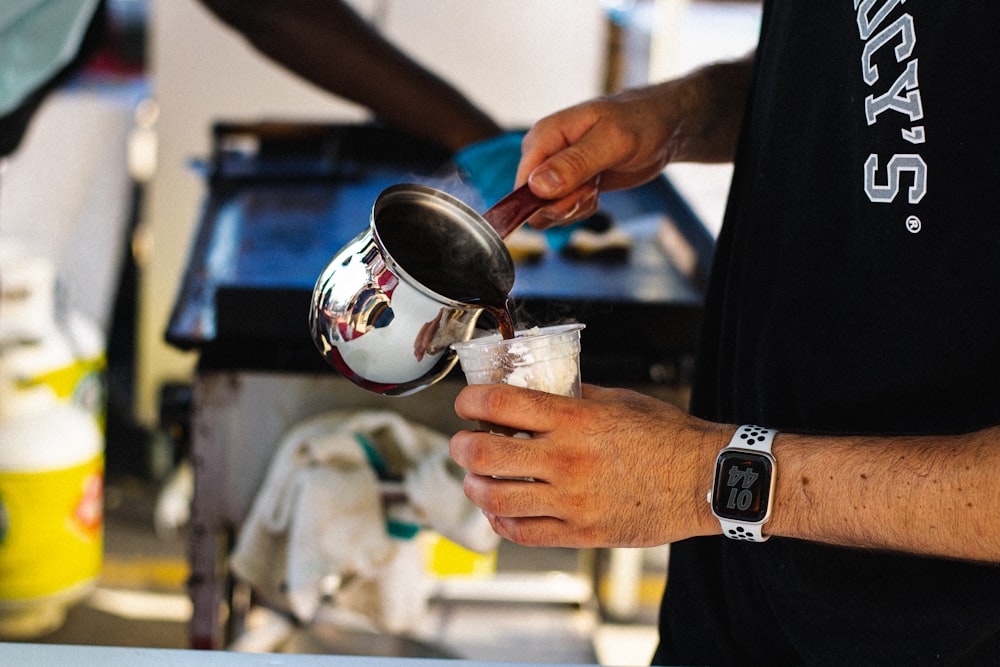 a person pouring something into a cup on a table