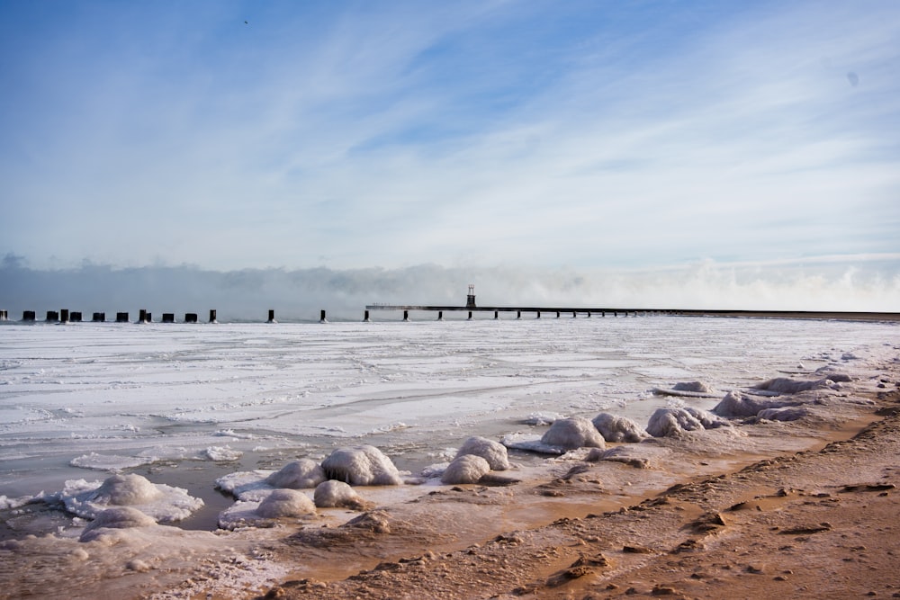 a beach covered in snow next to a pier