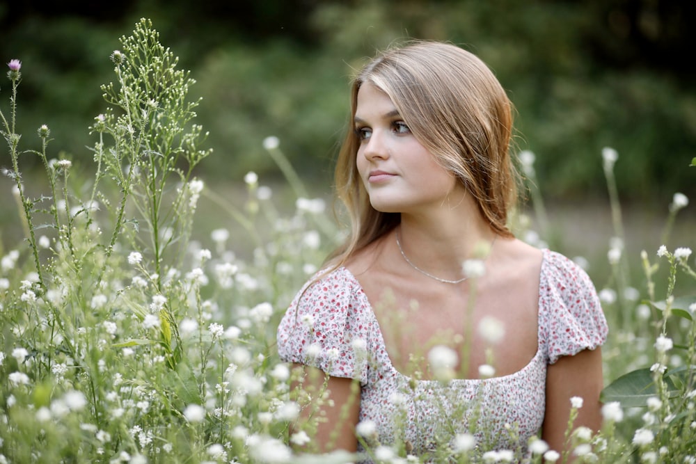 a beautiful young woman sitting in a field of flowers