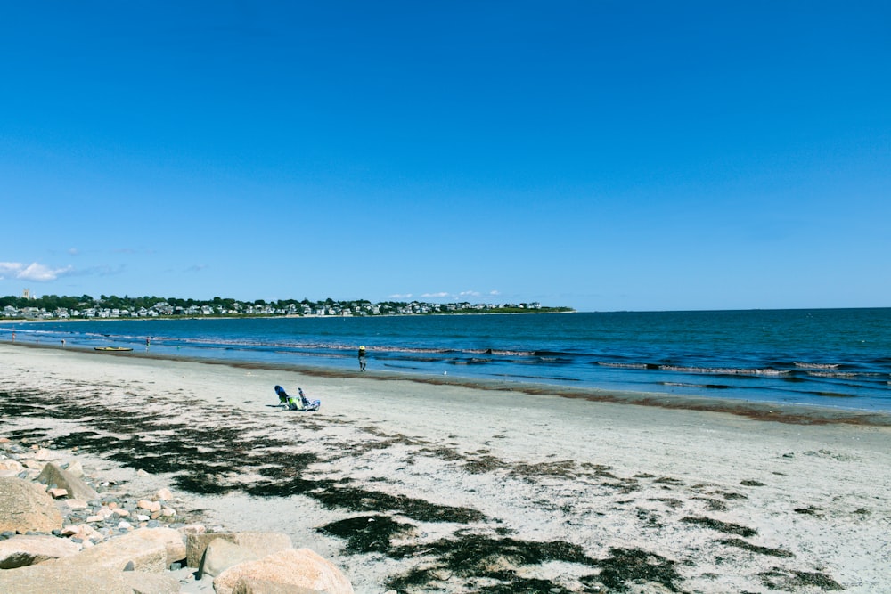 a couple of people sitting on top of a sandy beach