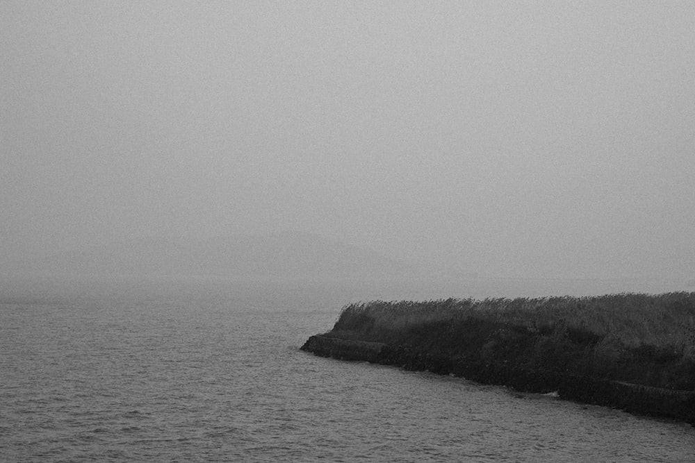 a black and white photo of a lighthouse on a foggy day