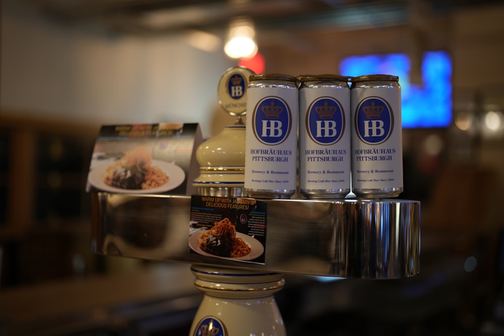 a silver plate topped with three cans of beer