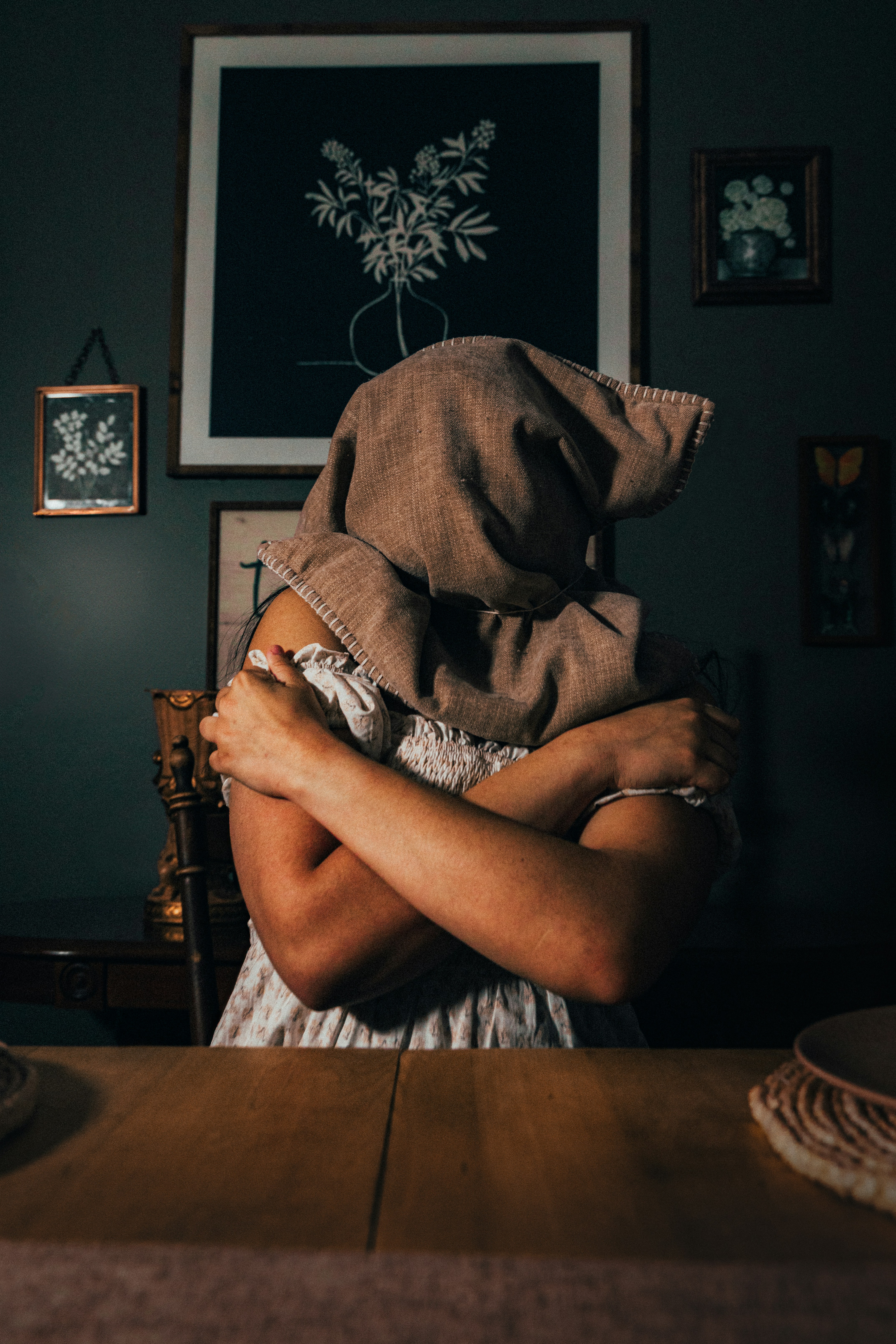 a woman with a hood on her head sitting at a table