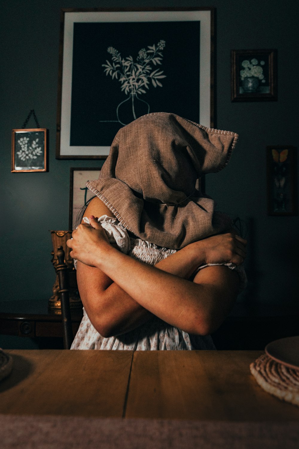 a woman with a hood on her head sitting at a table