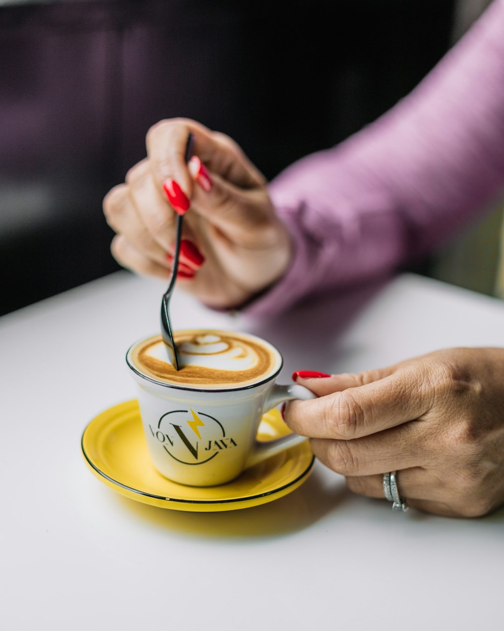 a woman holding a spoon in a cup of coffee