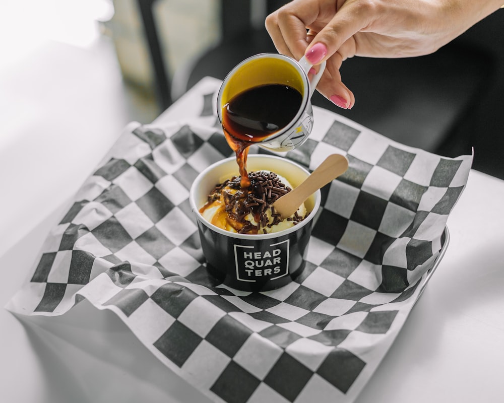 a person pouring sauce into a bowl of food