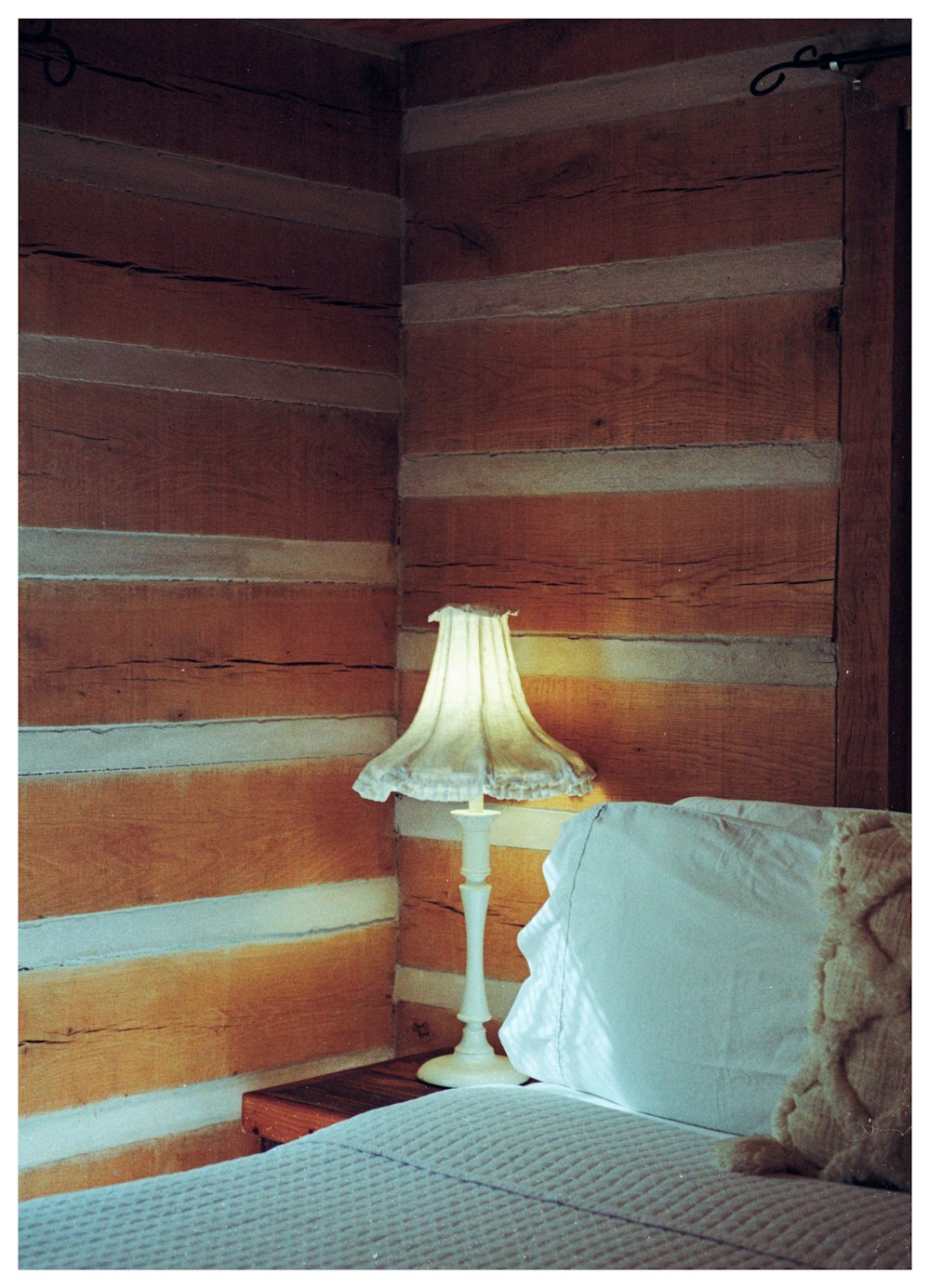 a bed with a lamp on top of it next to a wooden wall