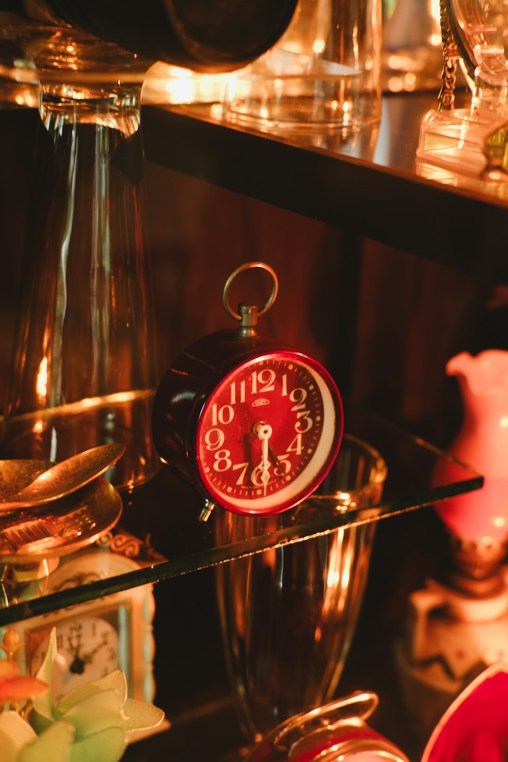 a red clock sitting on top of a glass shelf