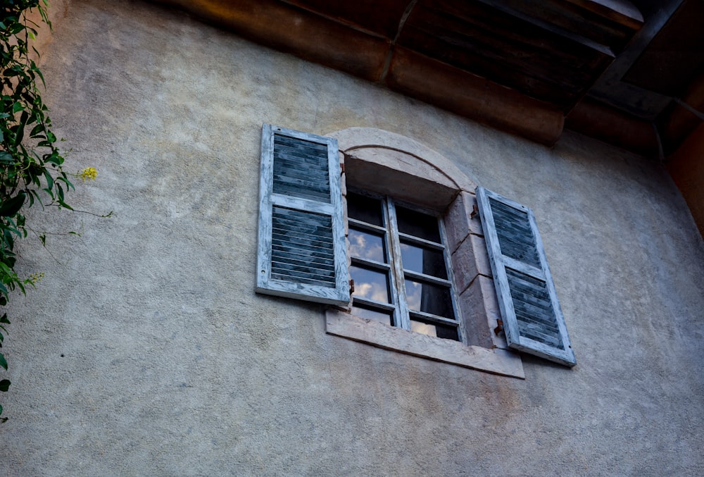 a building with a window and shutters on the side of it