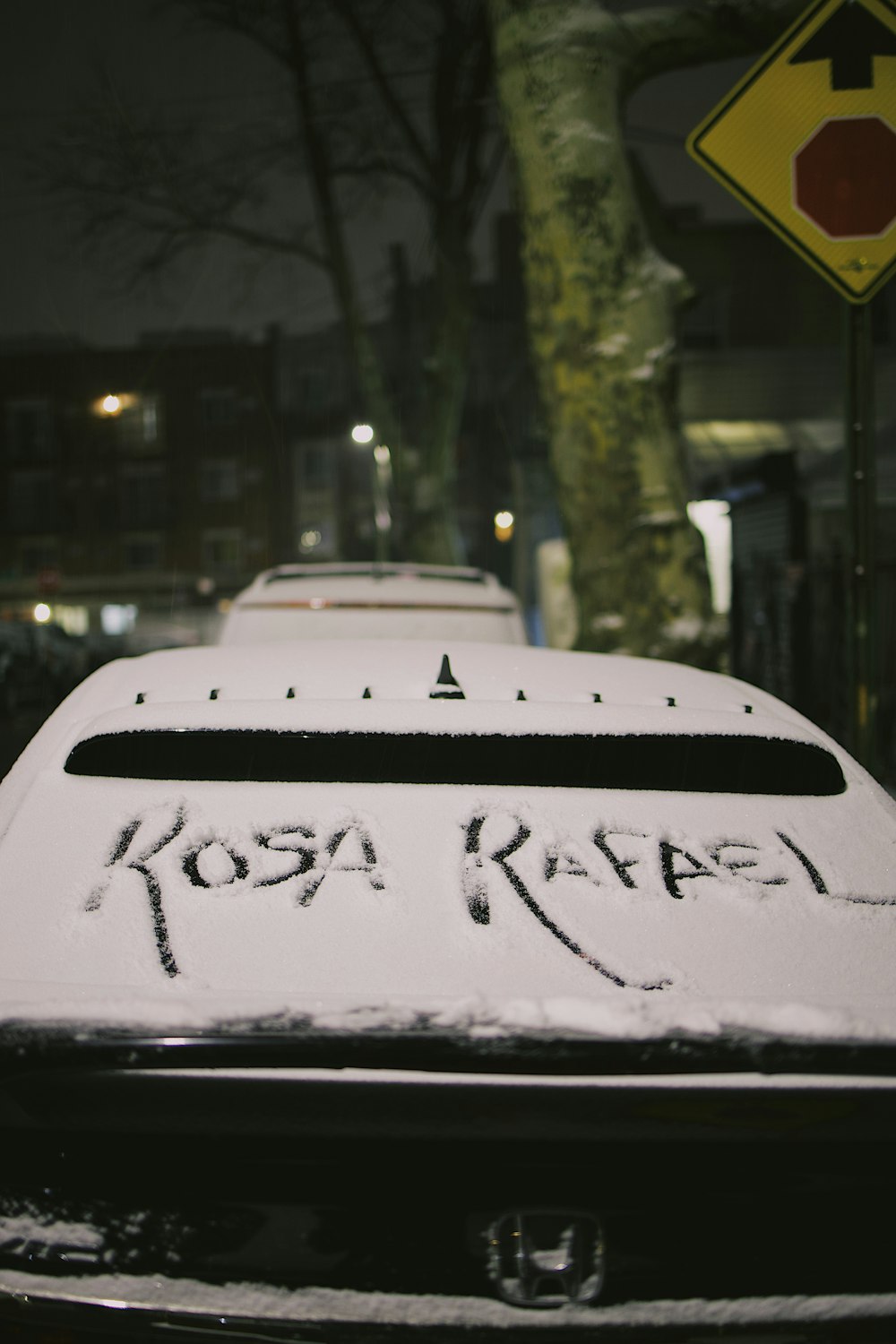 a car covered in snow next to a street sign