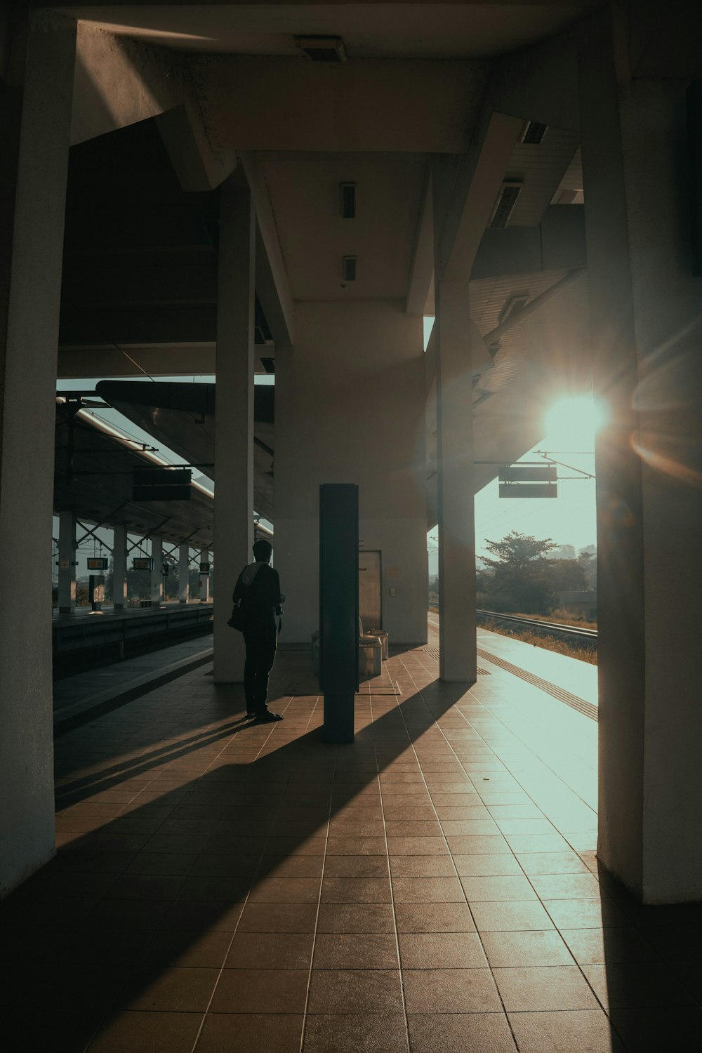 a person standing on a train platform at sunset