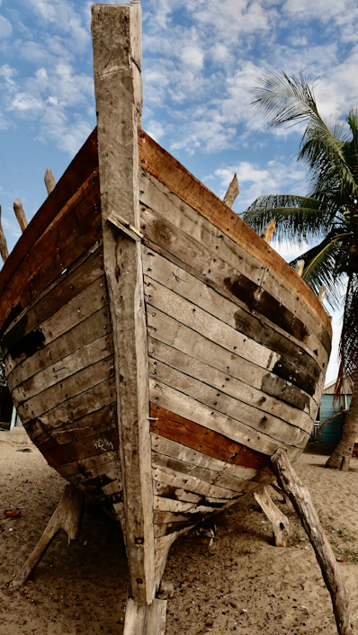 a wooden boat sitting on top of a sandy beach