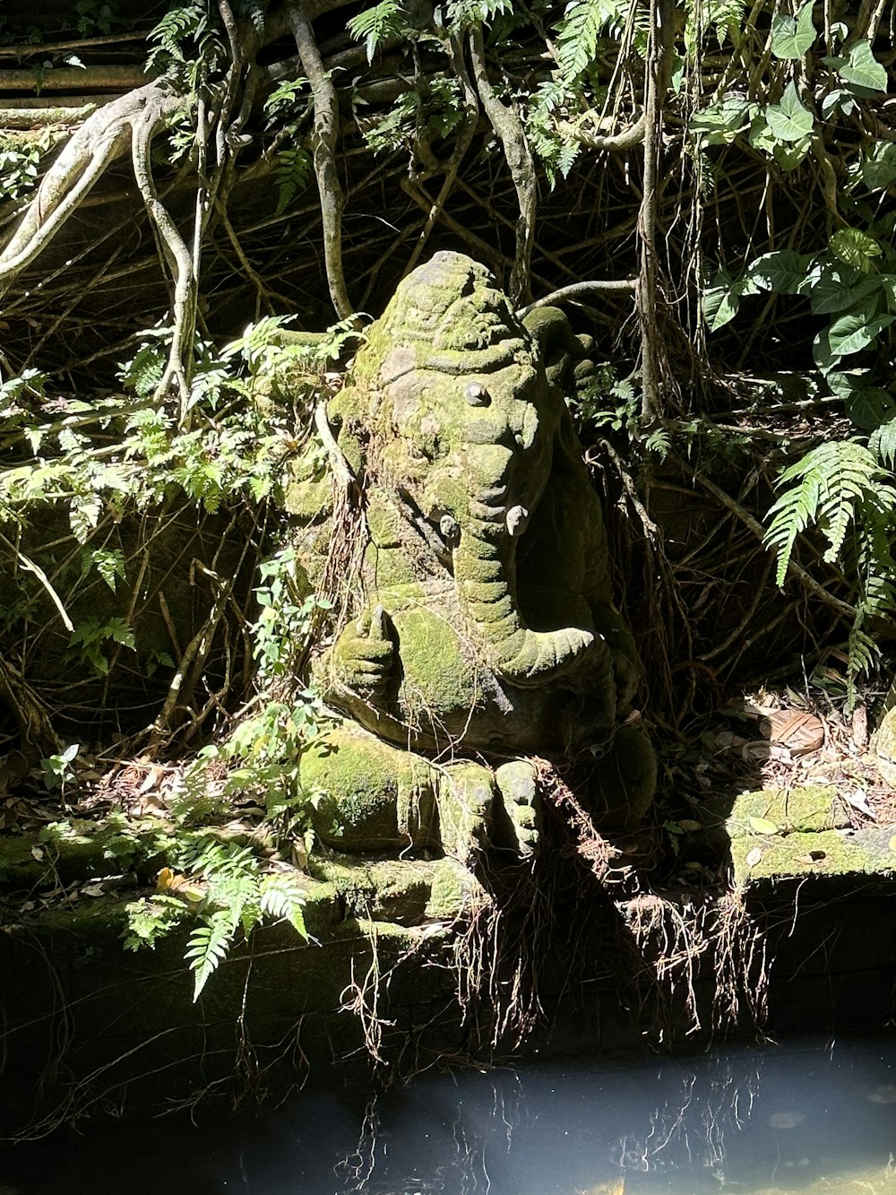a statue of an elephant in the middle of a forest