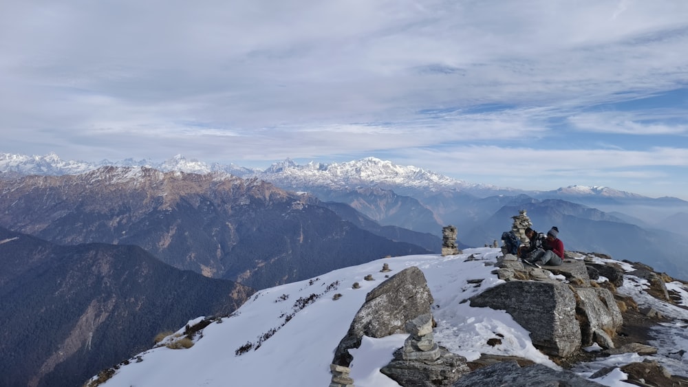 a group of people sitting on top of a snow covered mountain