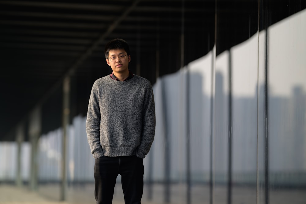 a man standing in front of a wall with his hands in his pockets