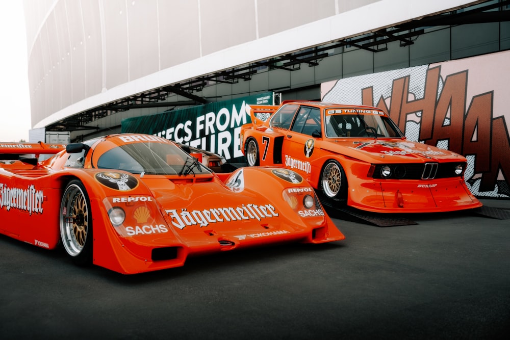 two orange race cars parked next to each other