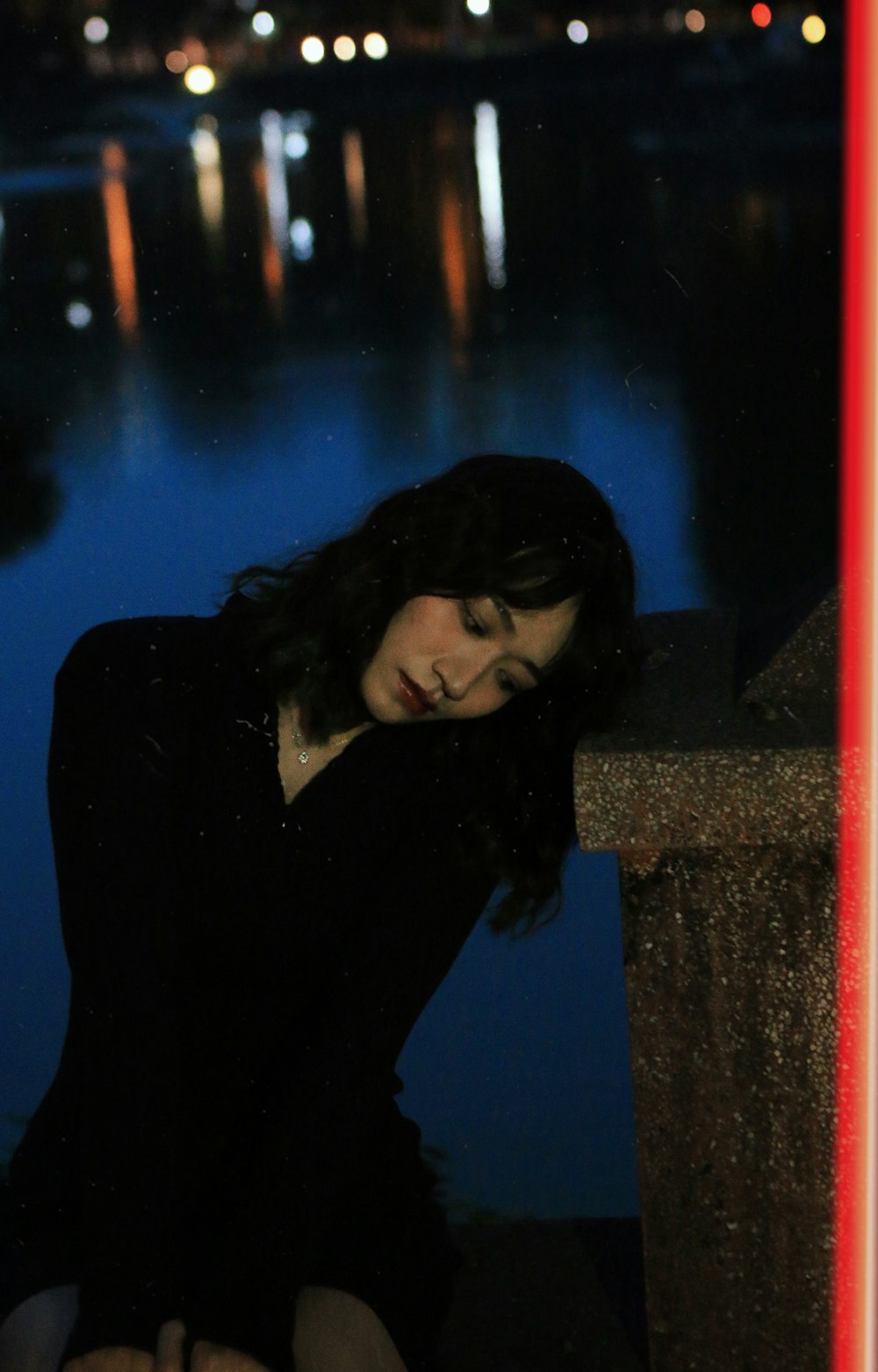 a woman sitting on a ledge next to a body of water