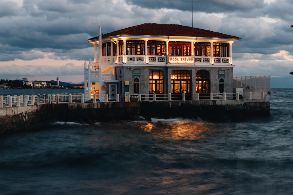 a house sitting on top of a pier next to the ocean