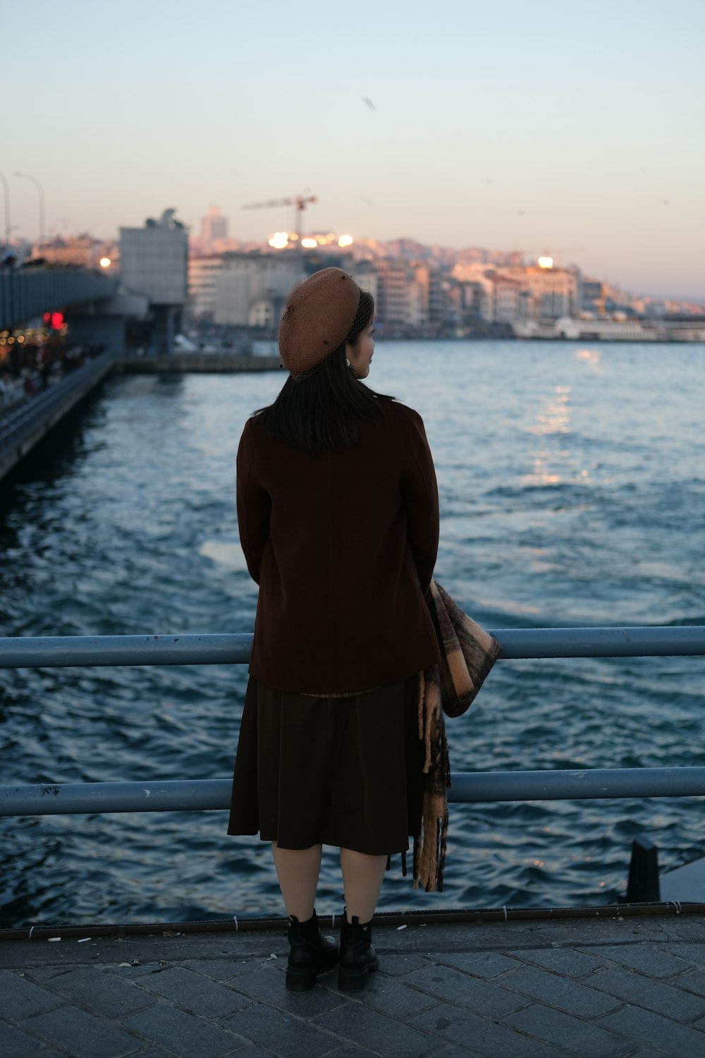 a woman standing on a pier looking at the water