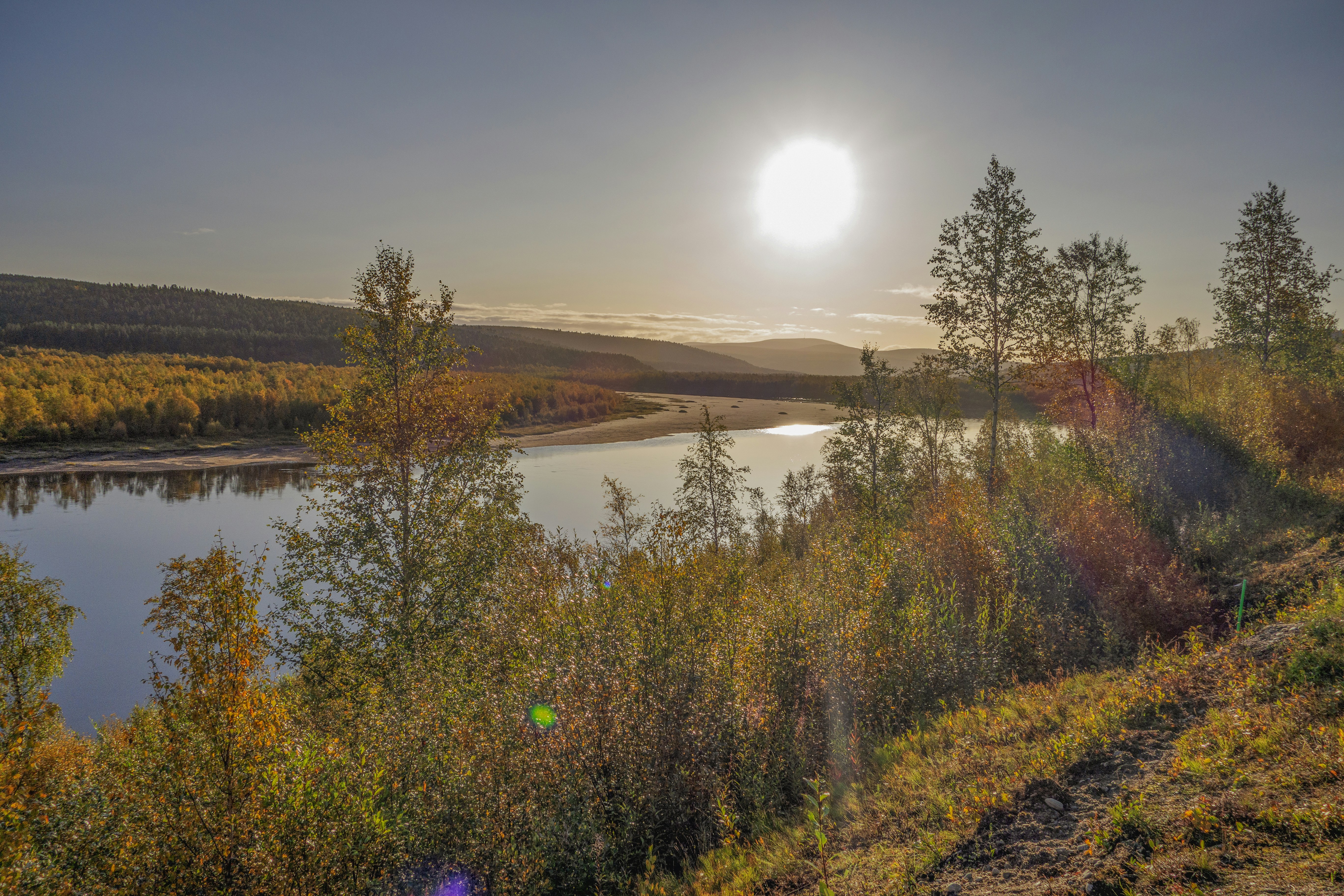 the sun is setting over a lake surrounded by trees