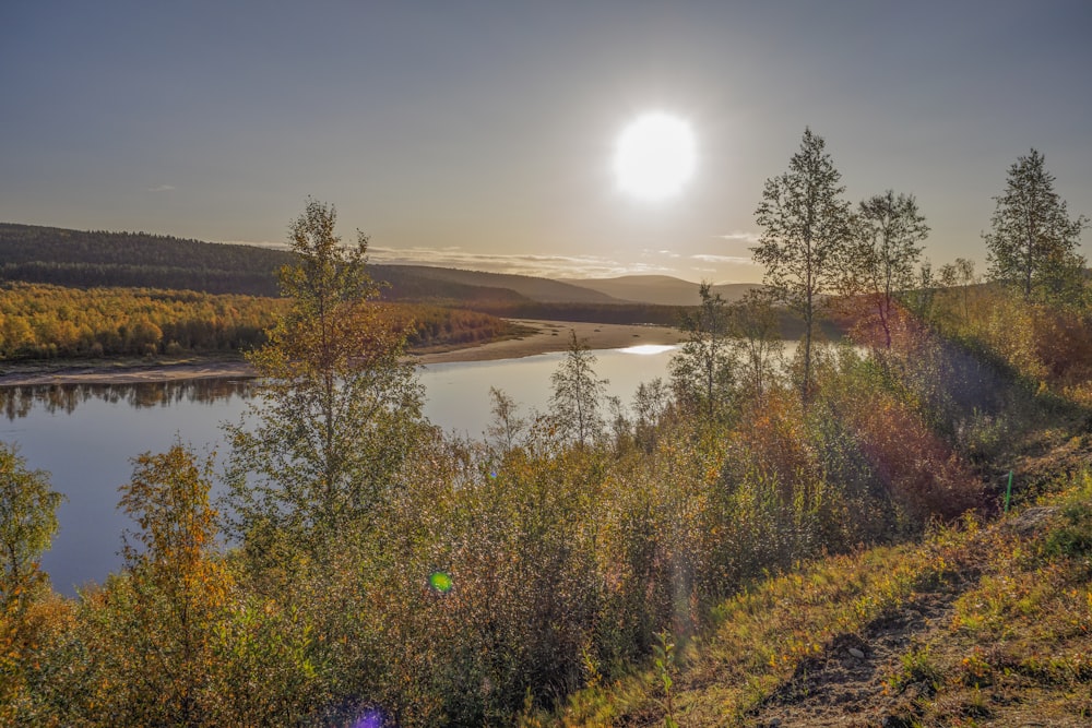 the sun is setting over a lake surrounded by trees