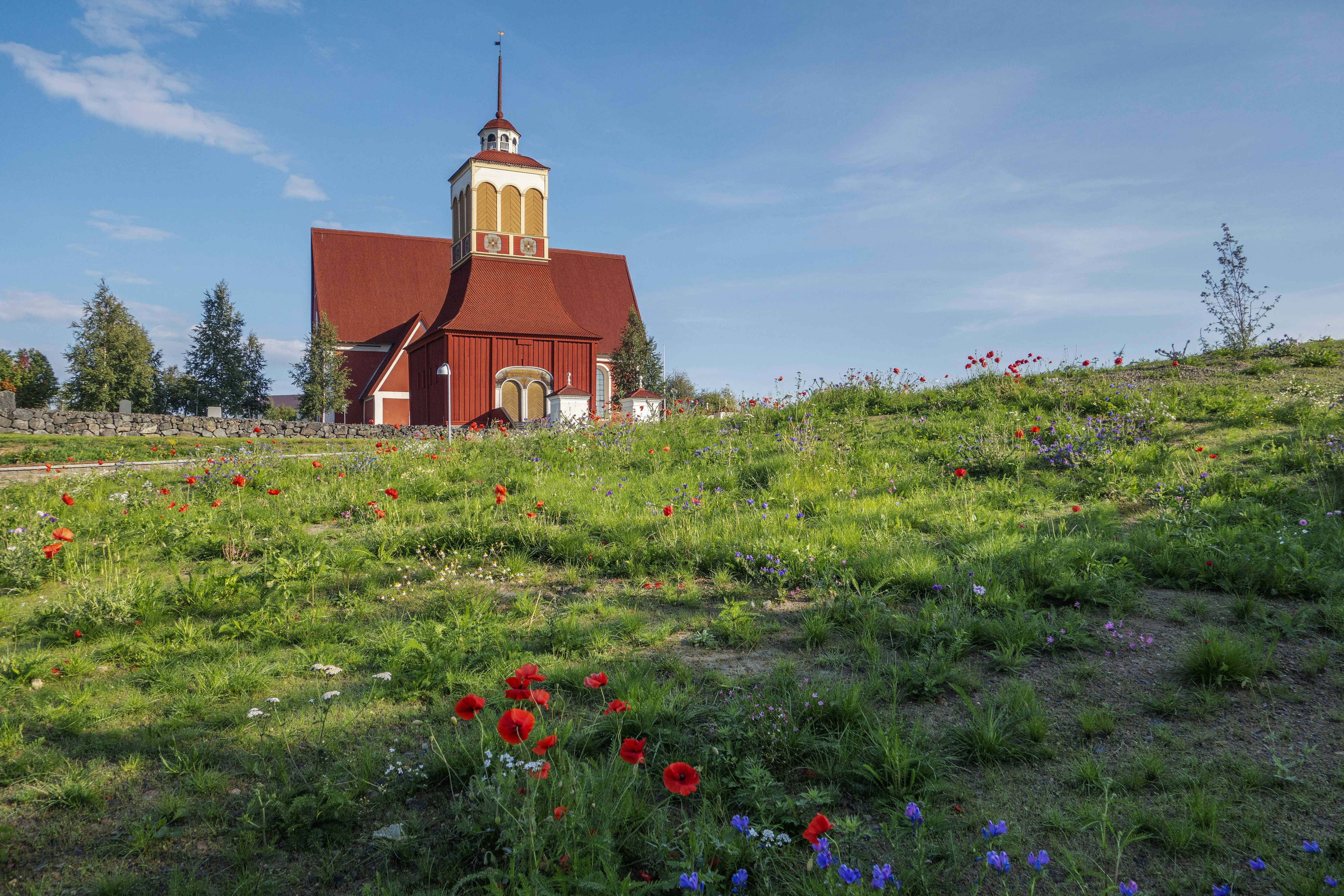 a red church with a steeple on a hill