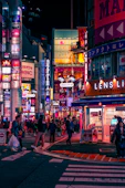 a busy city street at night with people crossing the street