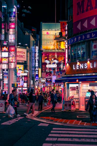 a busy city street at night with people crossing the street