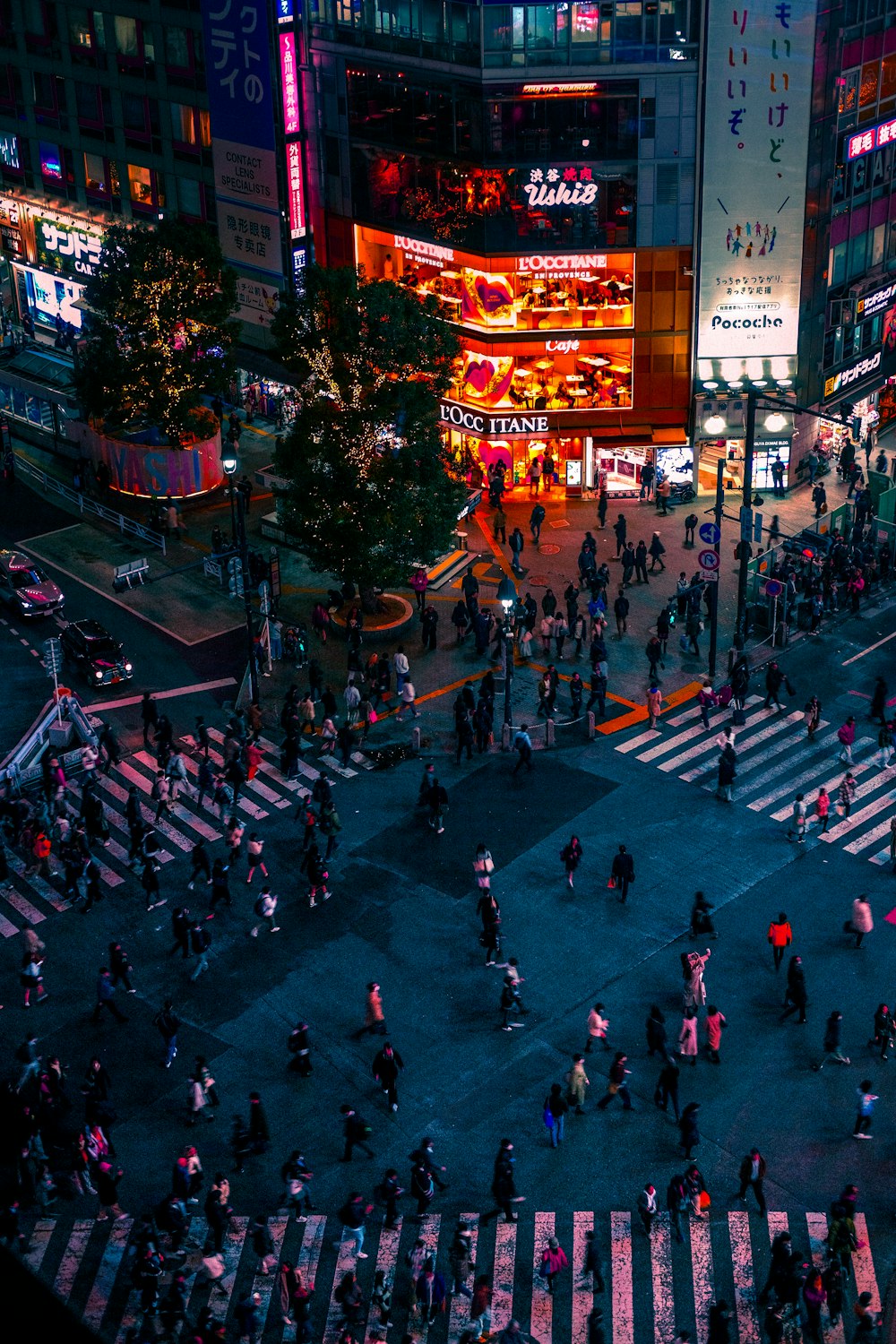 a crowded city street at night with people crossing the street