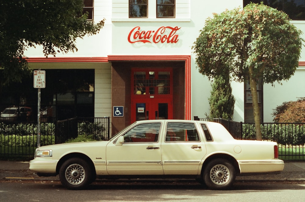 a white car parked in front of a coca cola store