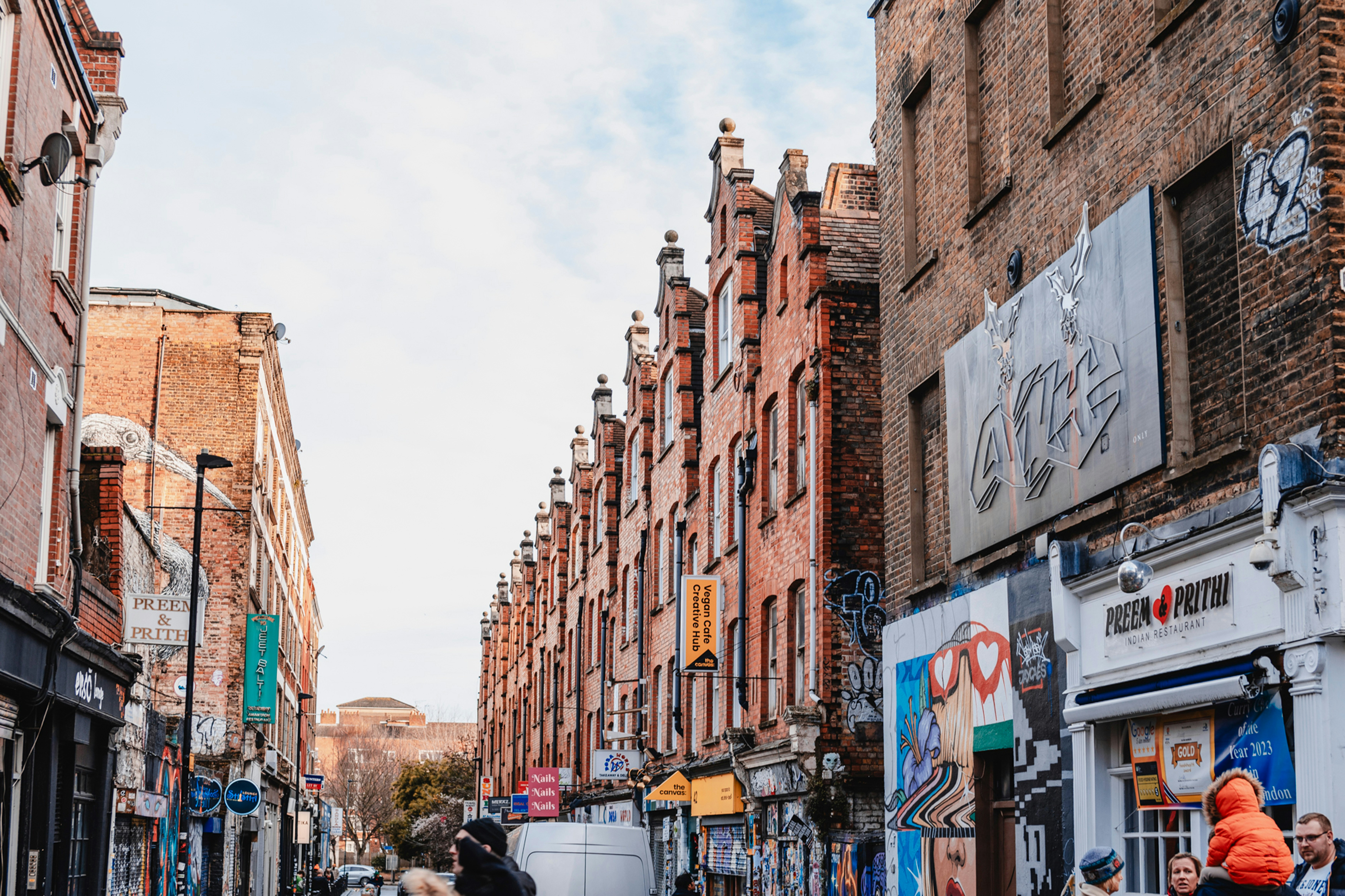 a group of people walking down a street next to tall buildings