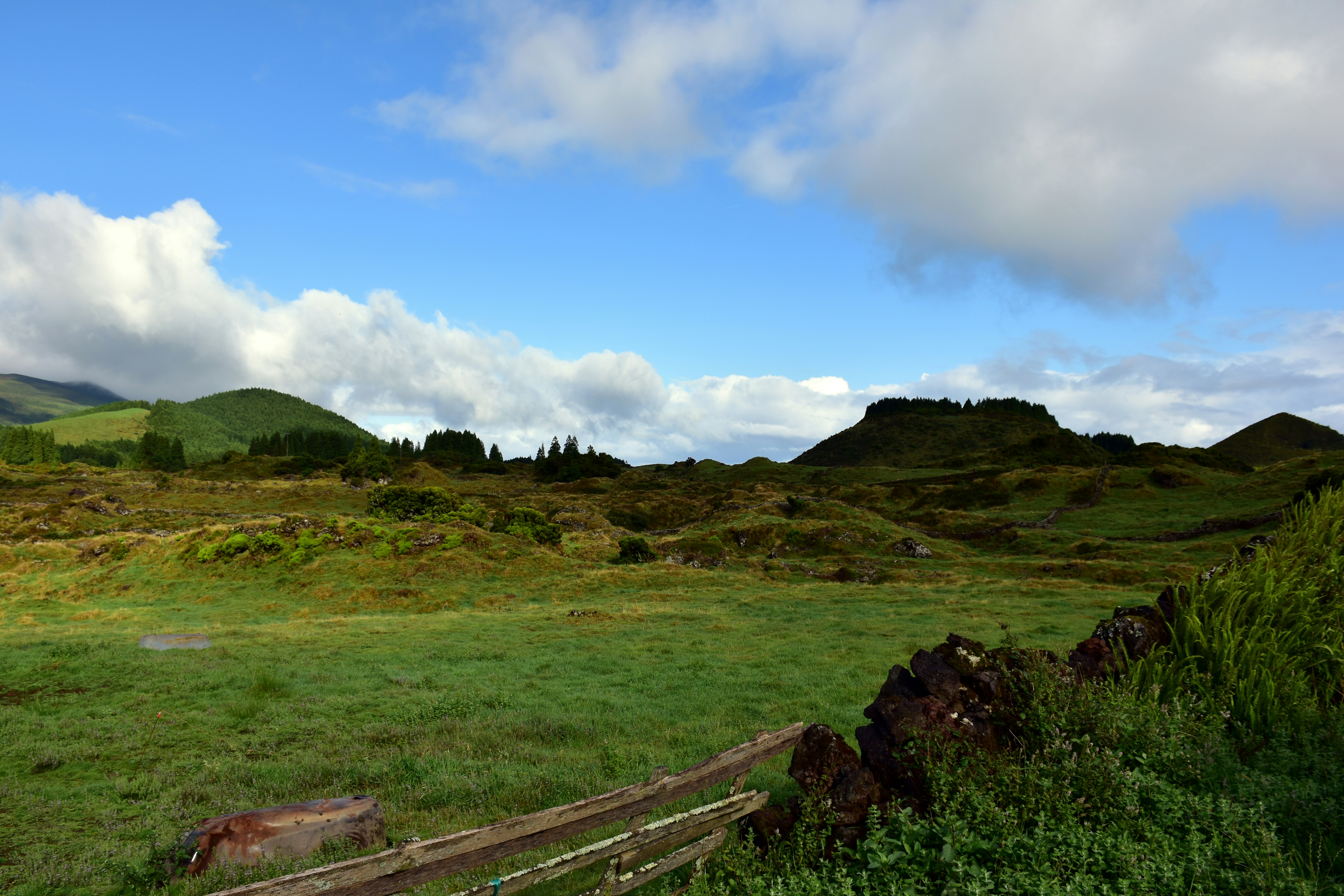 a grassy field with mountains in the background, A volcanic landscape (Beauty of nature)