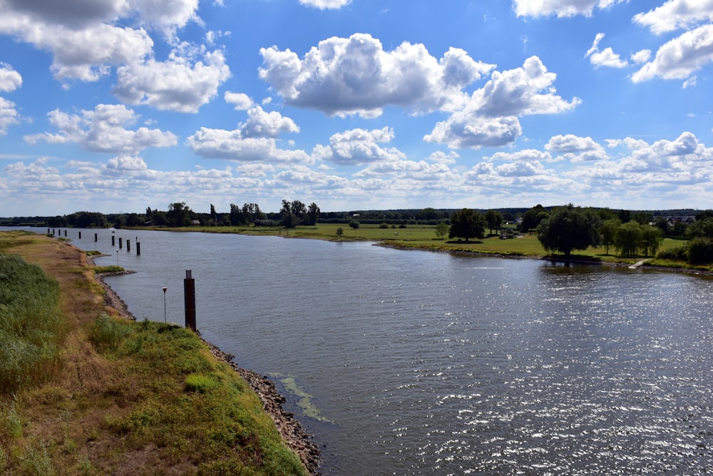 a body of water surrounded by a lush green field