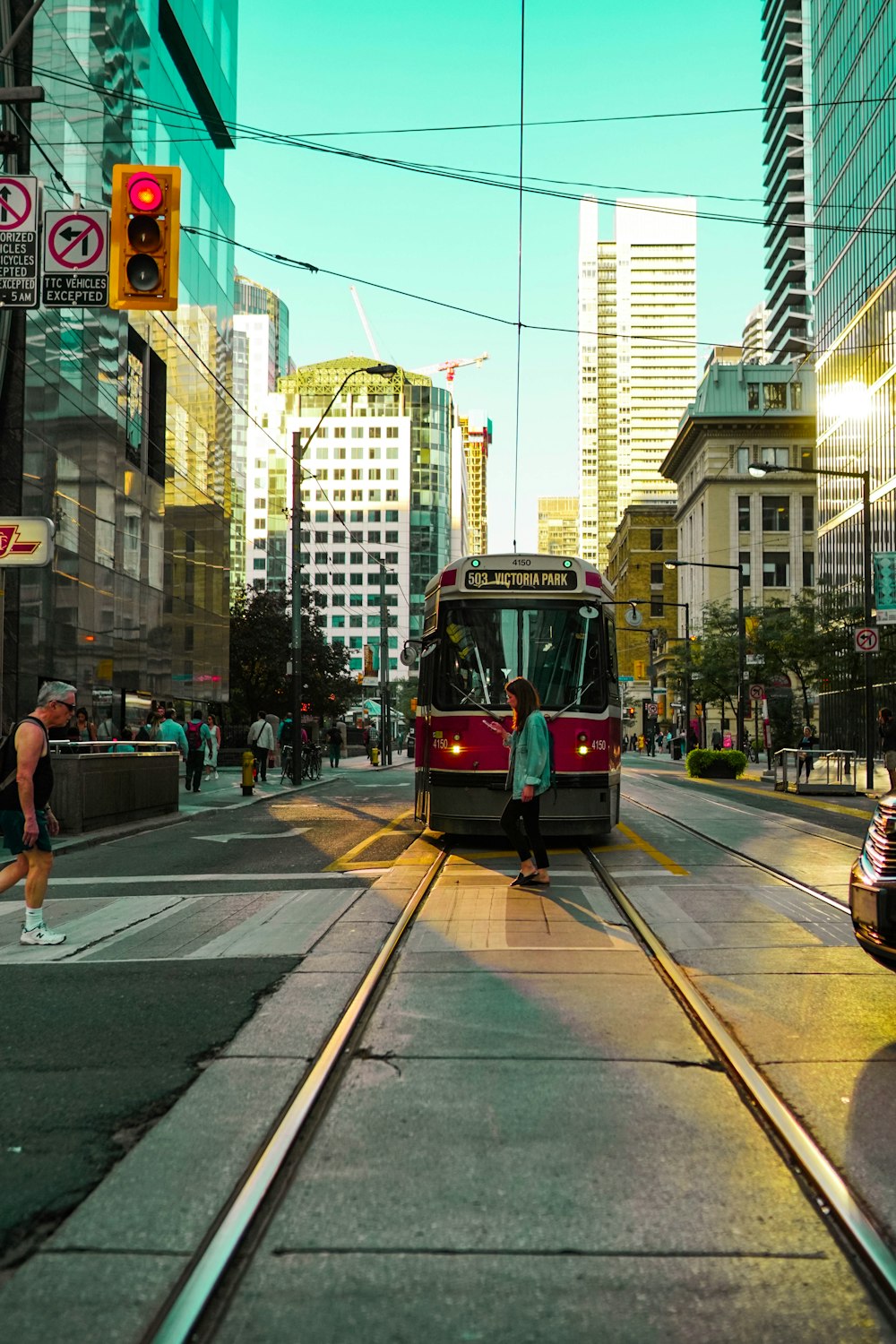 a red and black train traveling down a street next to tall buildings