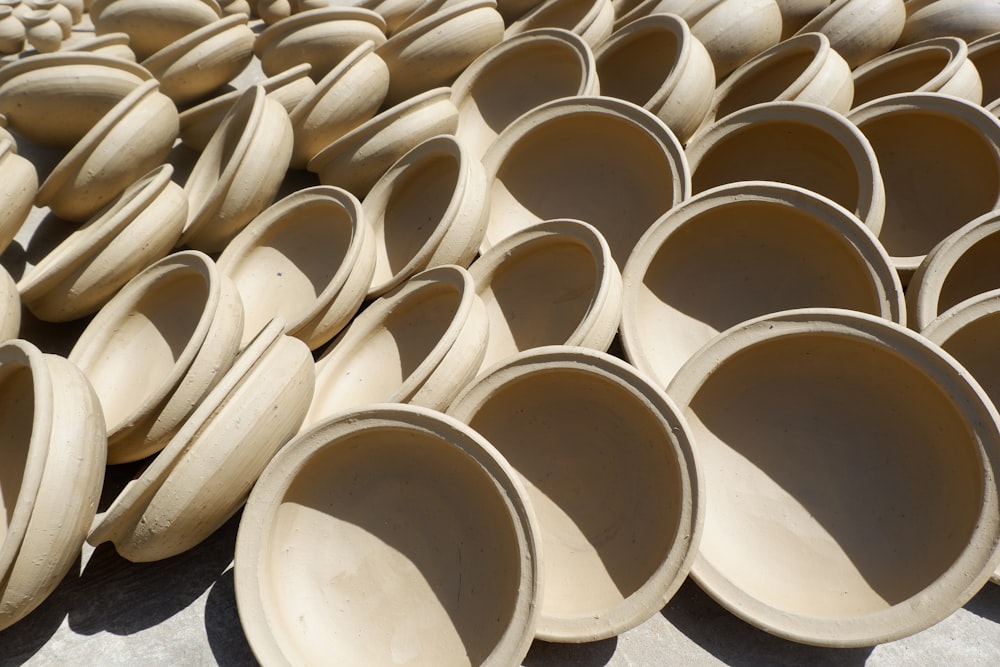 a pile of clay bowls sitting on top of a cement floor