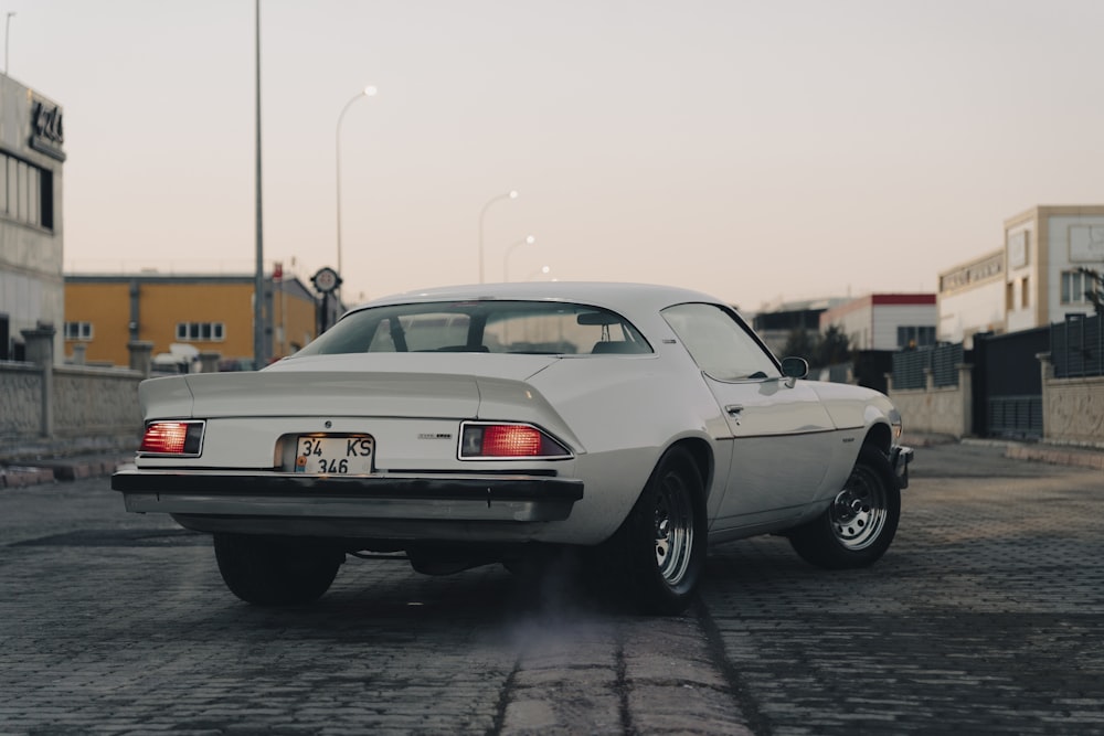 a white car is parked on a brick road