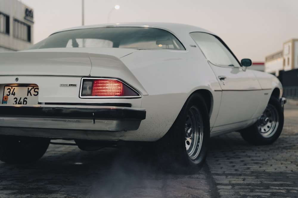 a white car is parked on a brick road