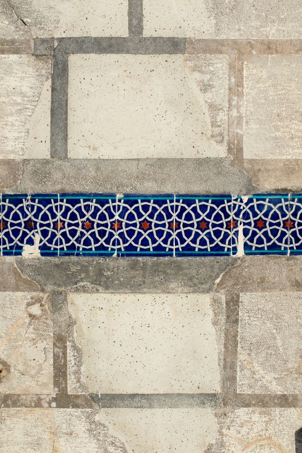 a blue and white tile border on a stone wall