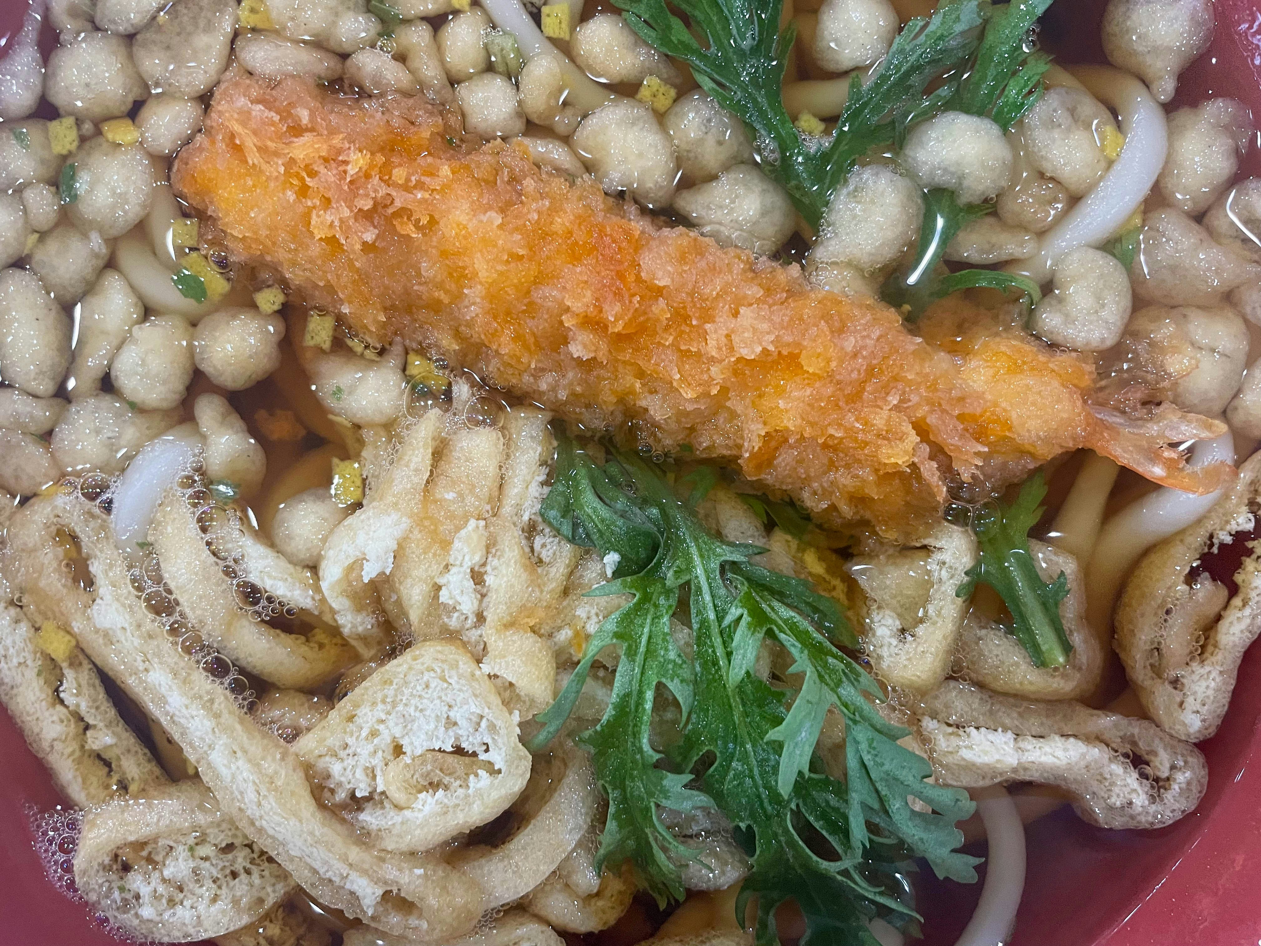 Udon soup topped with a tempura prawn and mushrooms